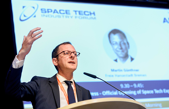 Martin Günthner am Rednerpult, Im Hintergrund ein Banner der Space Tech