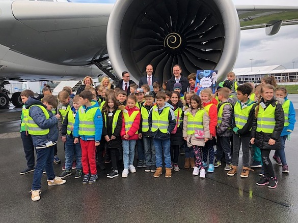 Eine große Schülergruppe vor einem Triebwerk der A350