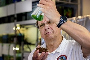 Ein Mann begutachtet eine grüne Flüssigkeit im Reagenzglas