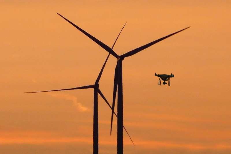 Windräder und eine Drone bei Sonnenuntergang