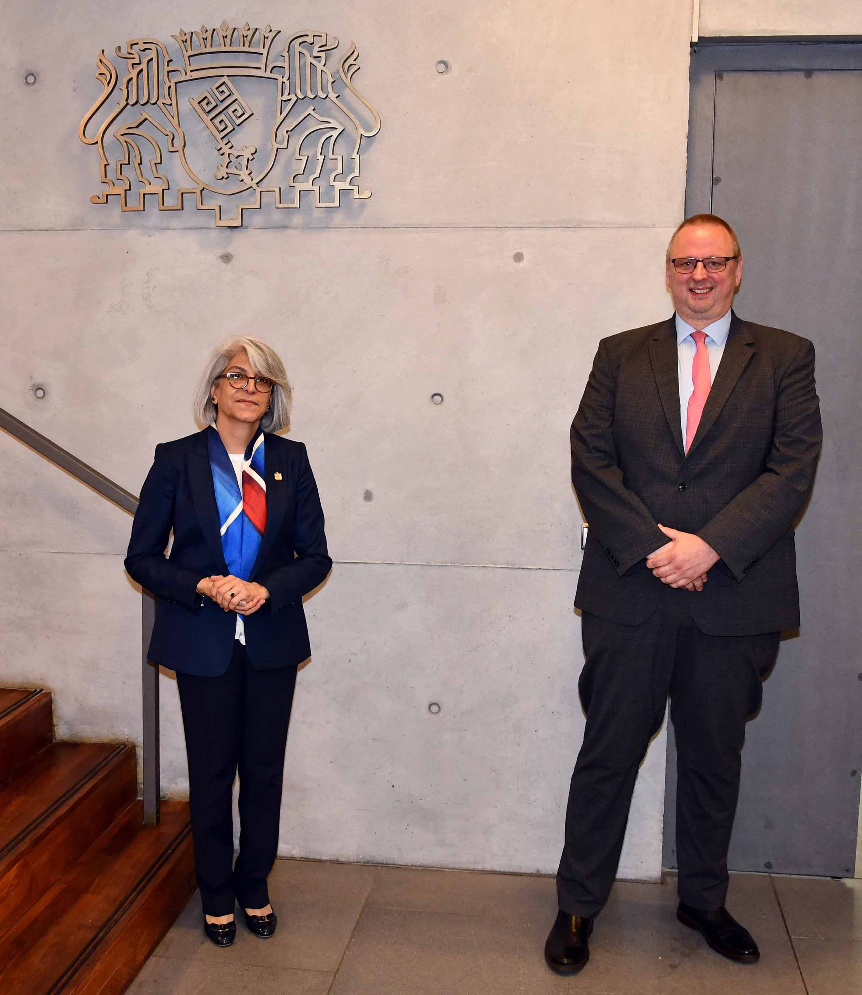 Staatsrat Joachim steht mit Botschafterin Alulama am Fuße einer Treppe