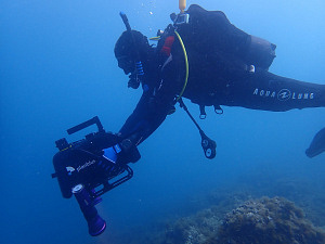Ein Taucher unter Wasser, der eine Kamera führt