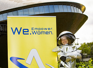 Eine Frau im Astronautinnenanzug, sowie ein Plakat zur We - Women Empower