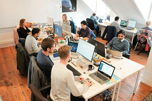 Einige Personen sitzen am Arbeitsplatz vor dem Laptop