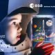 Ein Kopf eines Kindes im gebastelten Astronautenhelm schaut in ein Glas, in dem eine Raketenabbildung abhebt