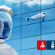 Ein Kopf im Astronauten-Helm, im Hintergrund eine sich Glaswand, auf der ein Flugzeug zu sehen ist