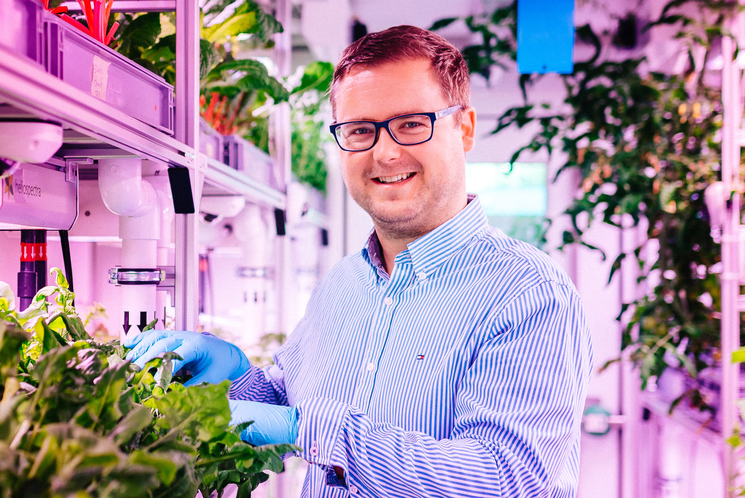 Mann posiert in einem wissenschaftlichen Gewächshaus