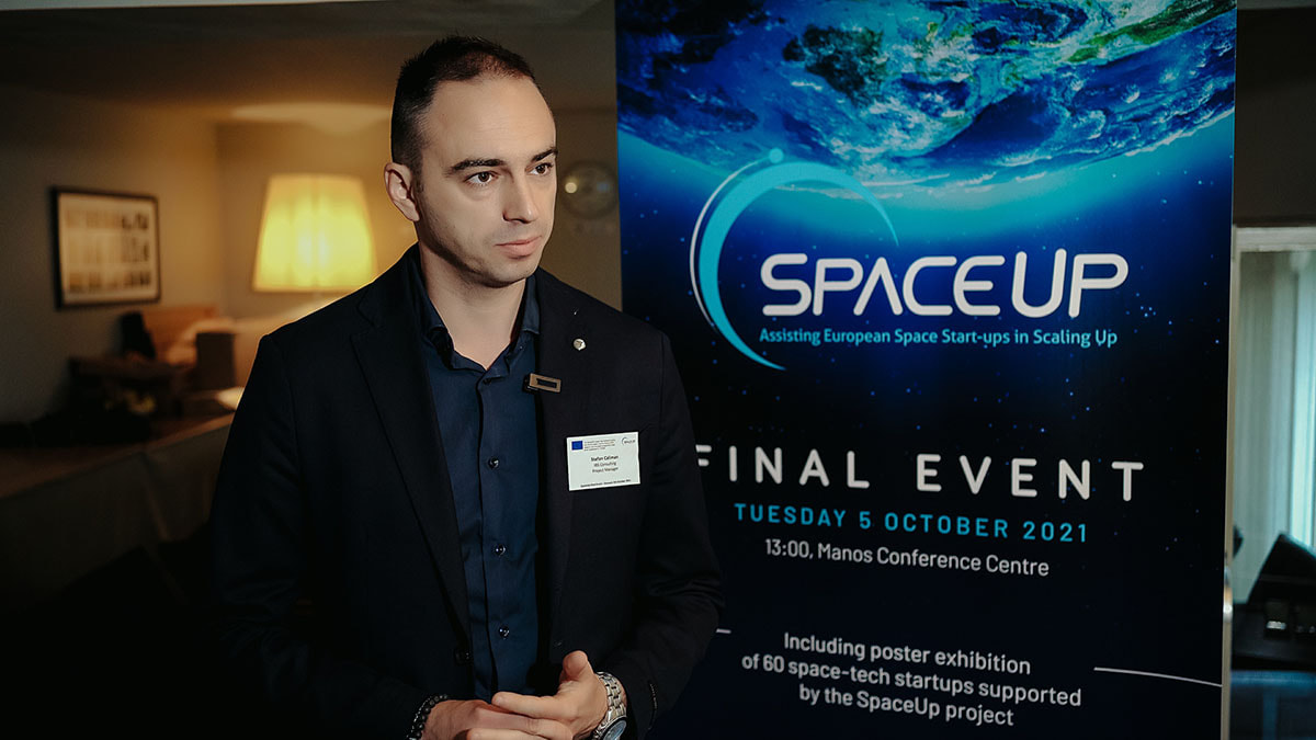 Ein Mann im Anzug steht vor einem Space-Up-Plakat