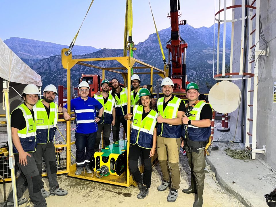 Team Foto with people with yellow vests on and a robot.